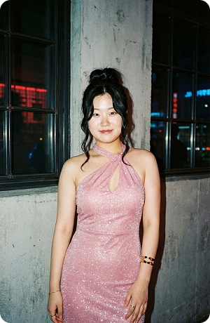 A coach in a pink dress on a city street at night